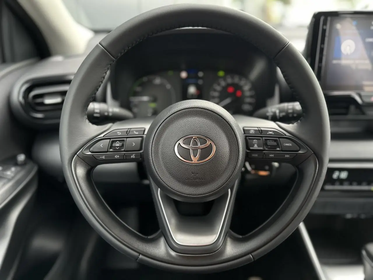 Volant en cuir noir de la Toyota Yaris Hybride 2025, vue frontale centrée sur les commandes multifonctions.