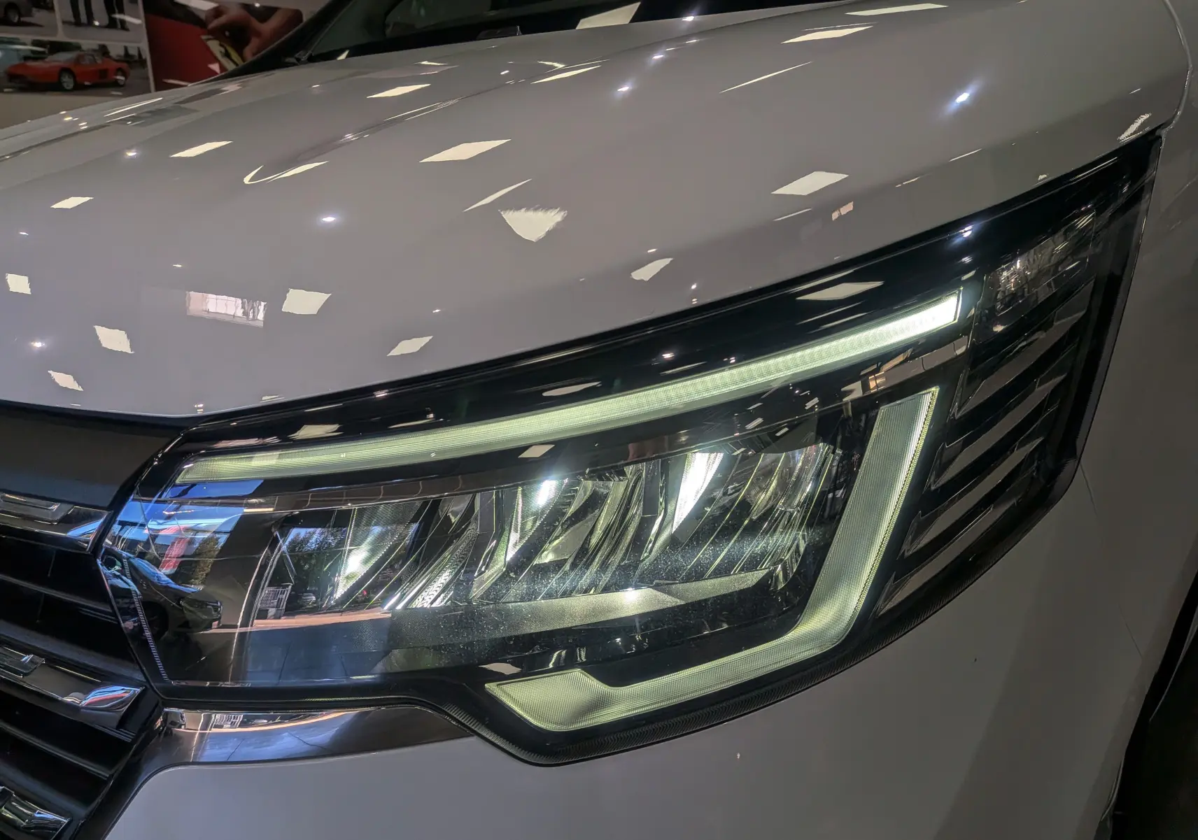 Gros plan sur le phare avant droit du Renault Trafic Combi blanc glacier 2025, mettant en valeur son design LED moderne.