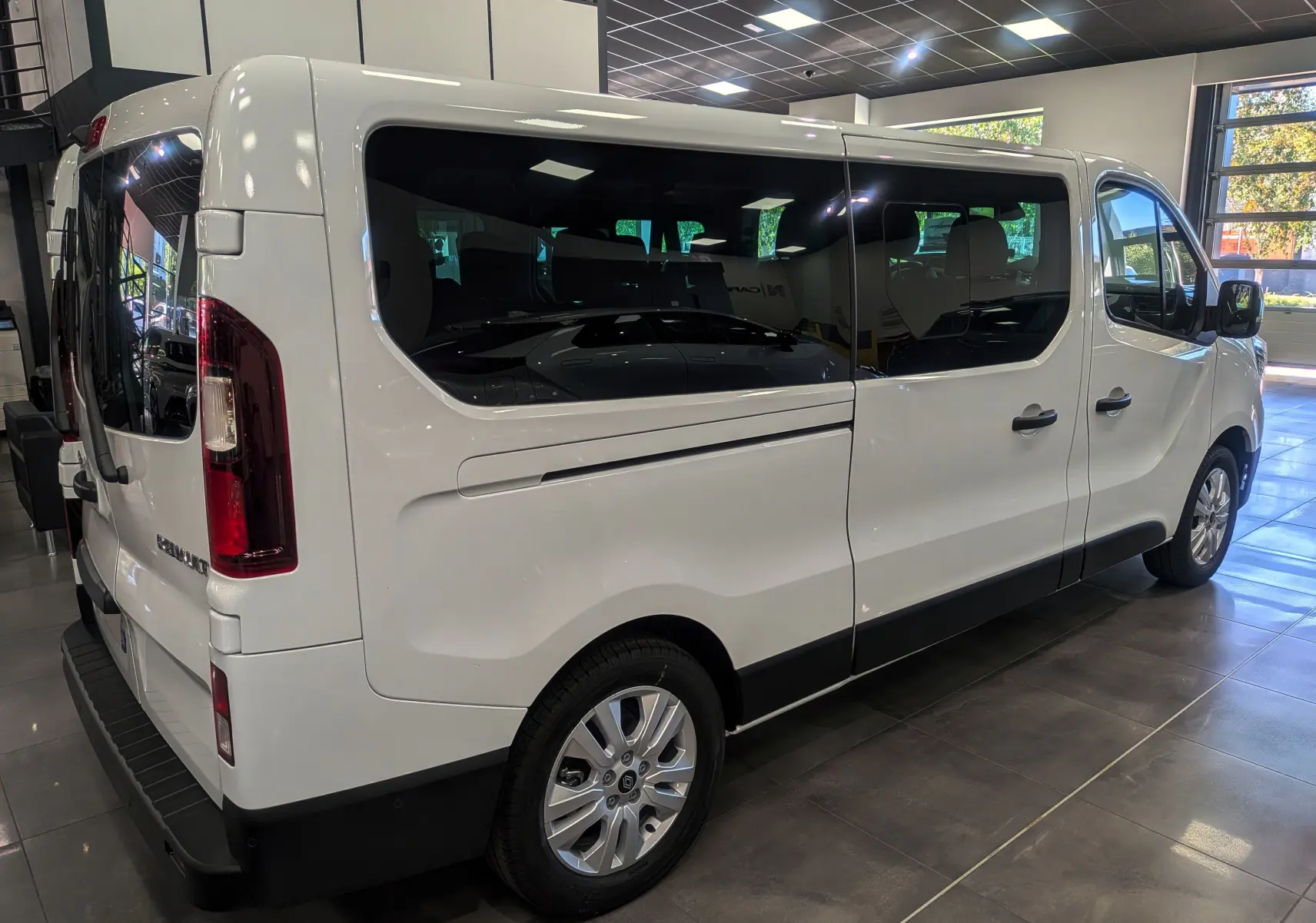 Renault Trafic Combi blanc glacier vu de trois quarts arrière droit, avec vitres teintées et jantes alliage.