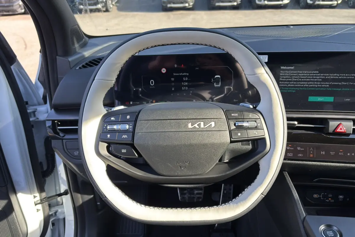 Vue rapprochée du volant cuir blanc nacré du Kia Sportage 2026 avec tableau de bord numérique et écran tactile.