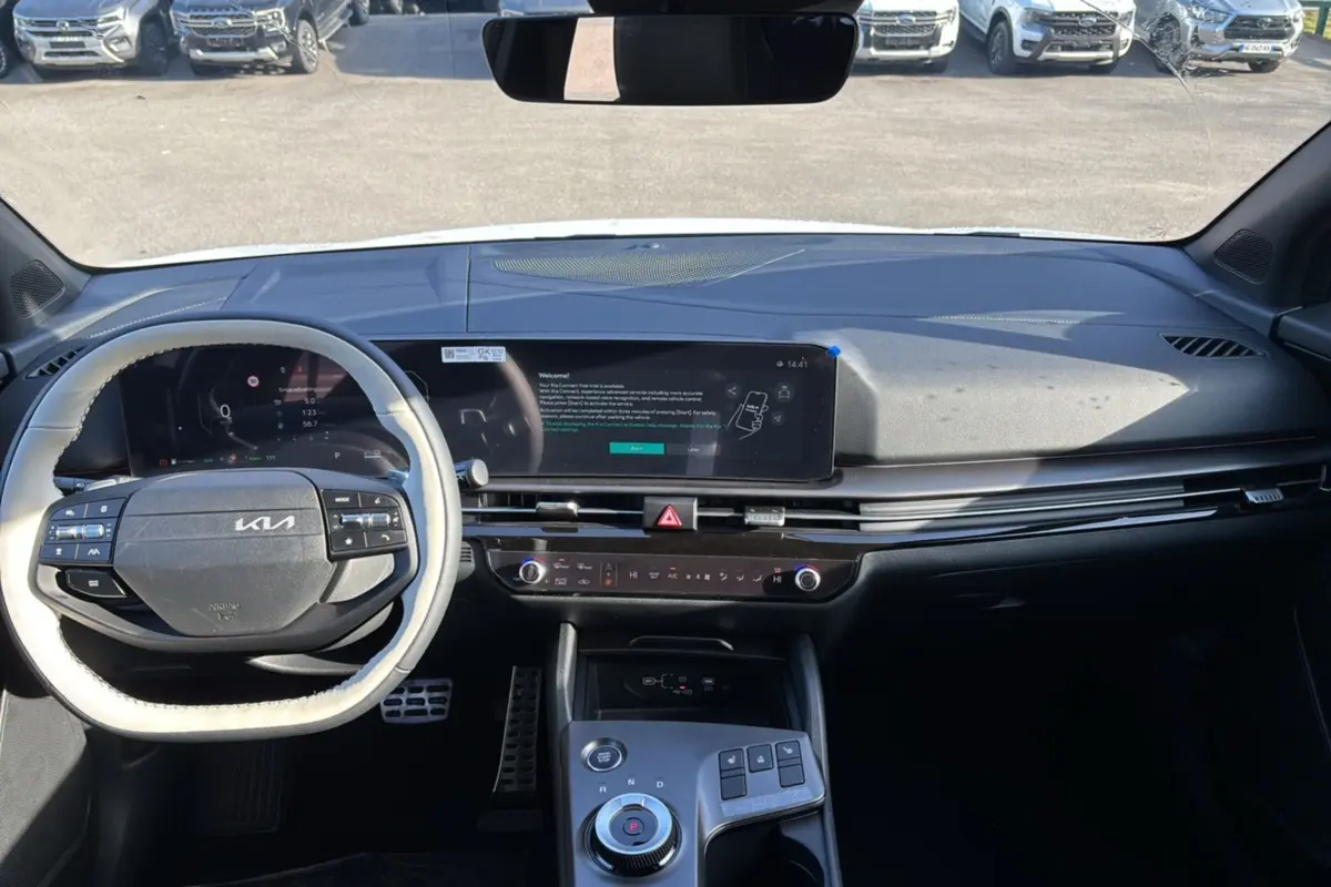 Vue intérieure du tableau de bord du Kia Sportage blanc nacré, avec volant cuir multifonctions et écran tactile panoramique.