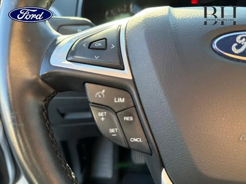 Gros plan sur le volant en cuir noir du Ford S-MAX gris lunaire, avec commandes de régulateur de vitesse et bouton OK.