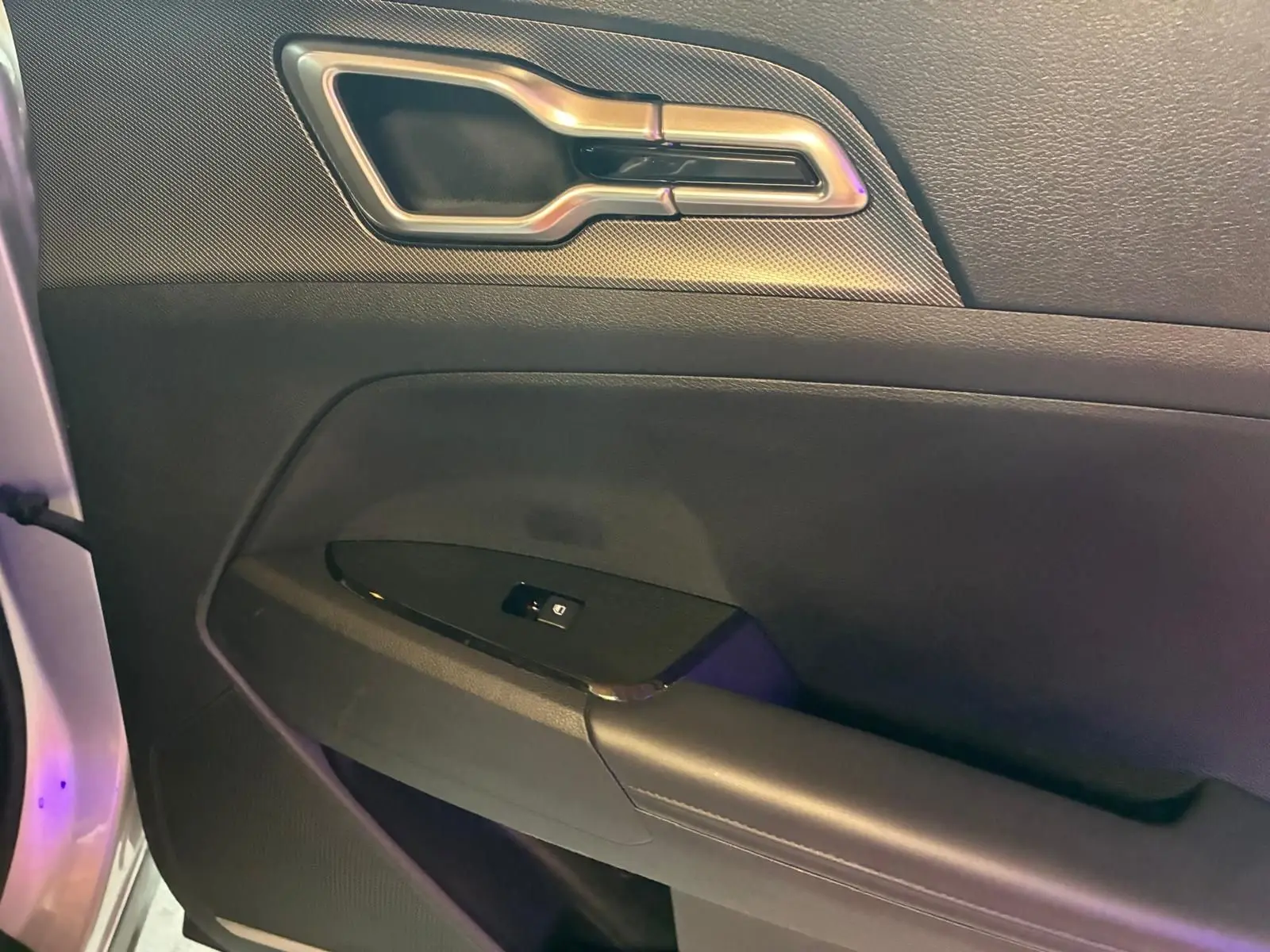 Gros plan sur la poignée intérieure et le panneau de porte côté gauche du KIA Sportage gris hybride 2024.