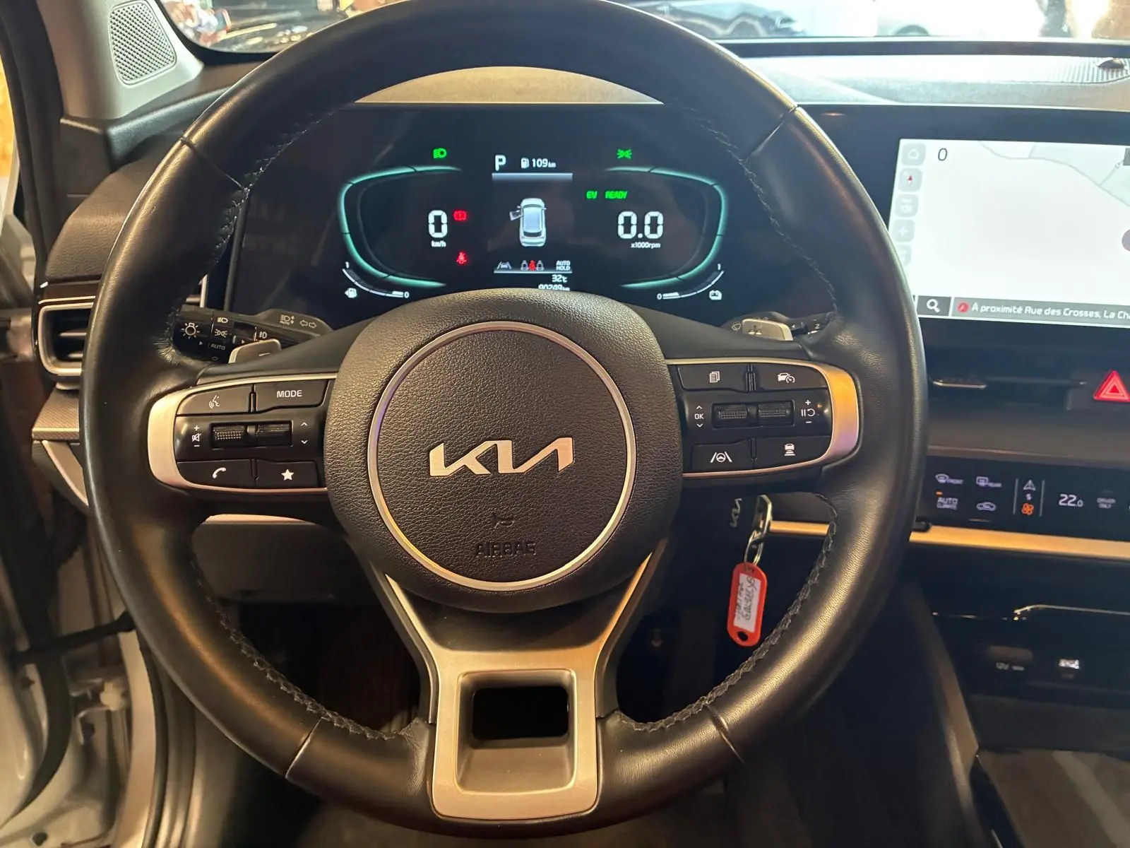 Vue rapprochée du volant noir du Kia Sportage 2024 hybride avec tableau de bord numérique et écran tactile.