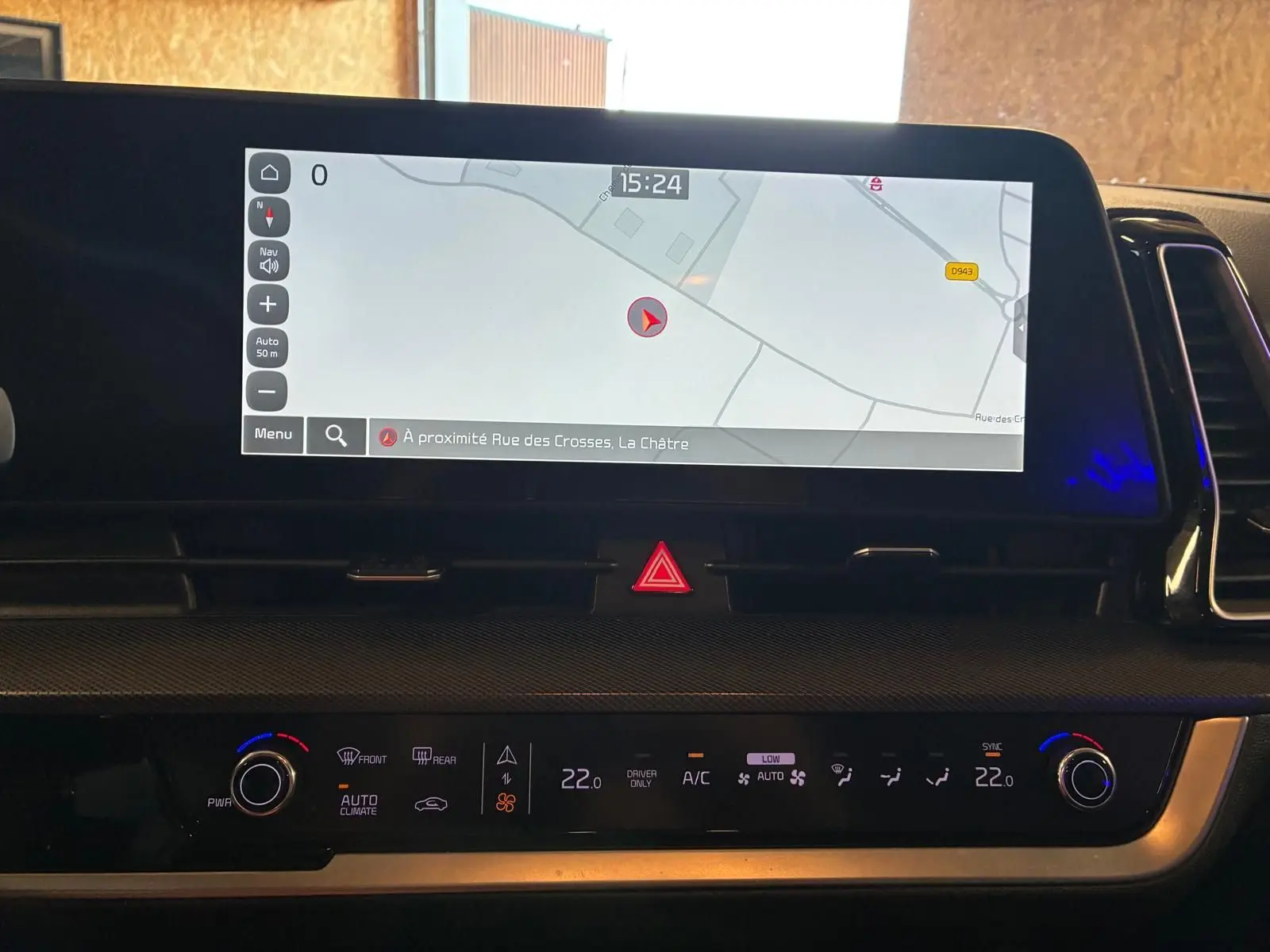 Vue intérieure du tableau de bord du Kia Sportage 2024 hybride, avec écran tactile de navigation et commandes climatisation.