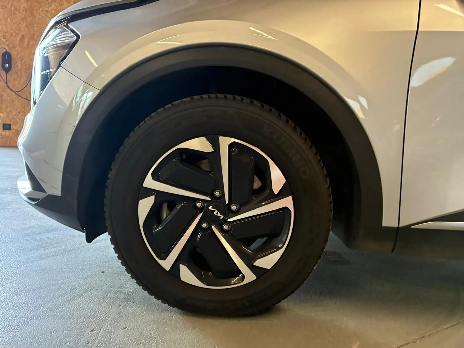 Gros plan sur la roue avant gauche du KIA Sportage gris 2024, mettant en valeur la jante noire et argentée au design moderne.