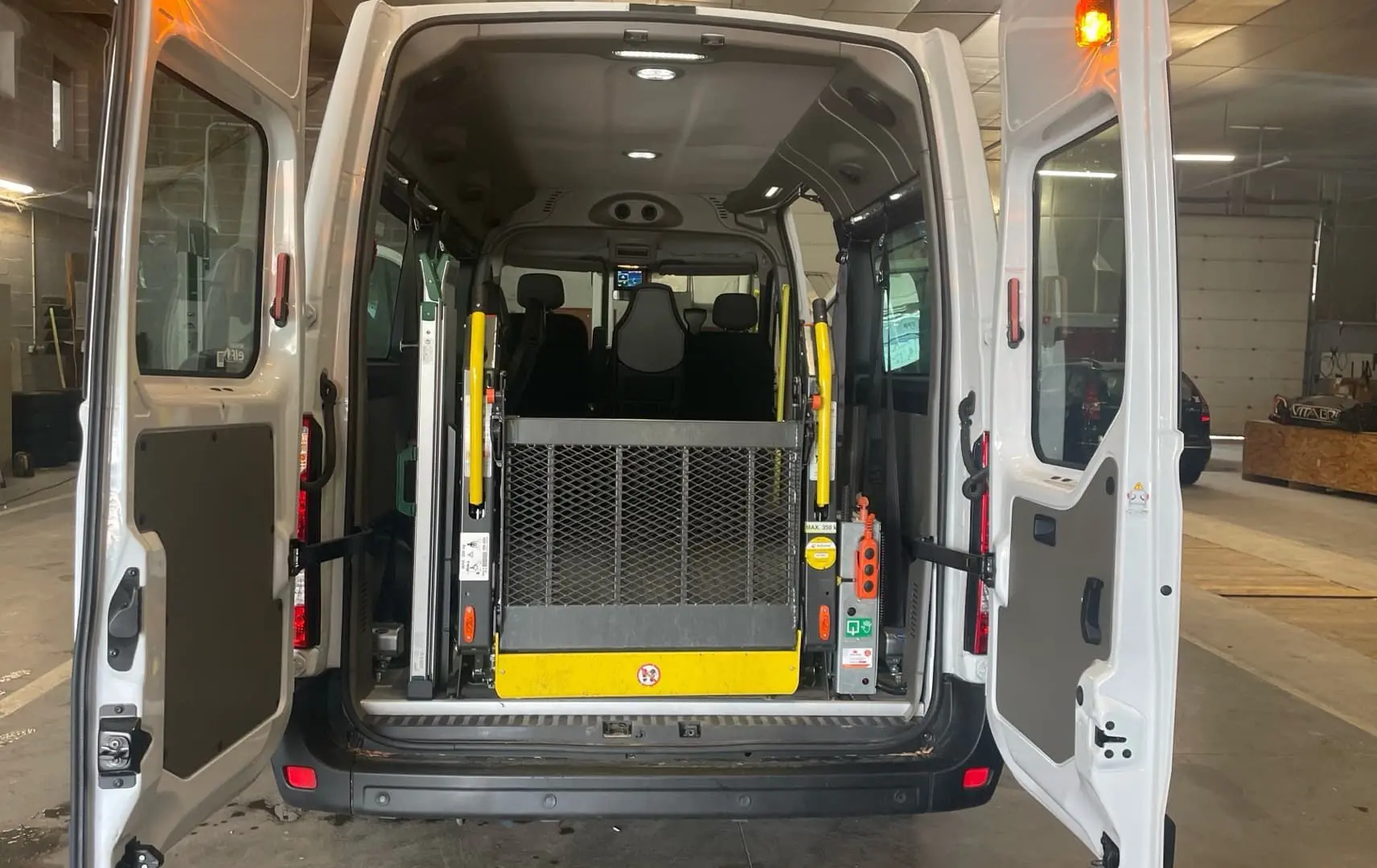 Vue arrière du Renault Master blanc avec portes ouvertes, mettant en valeur la rampe d'accès pour fauteuil roulant.