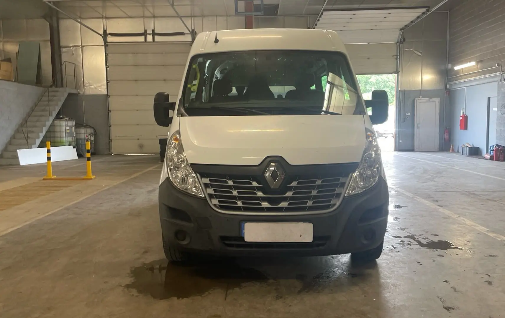 Vue de face d’un Renault Master blanc stationné en intérieur, avec calandre noire et grands rétroviseurs latéraux.