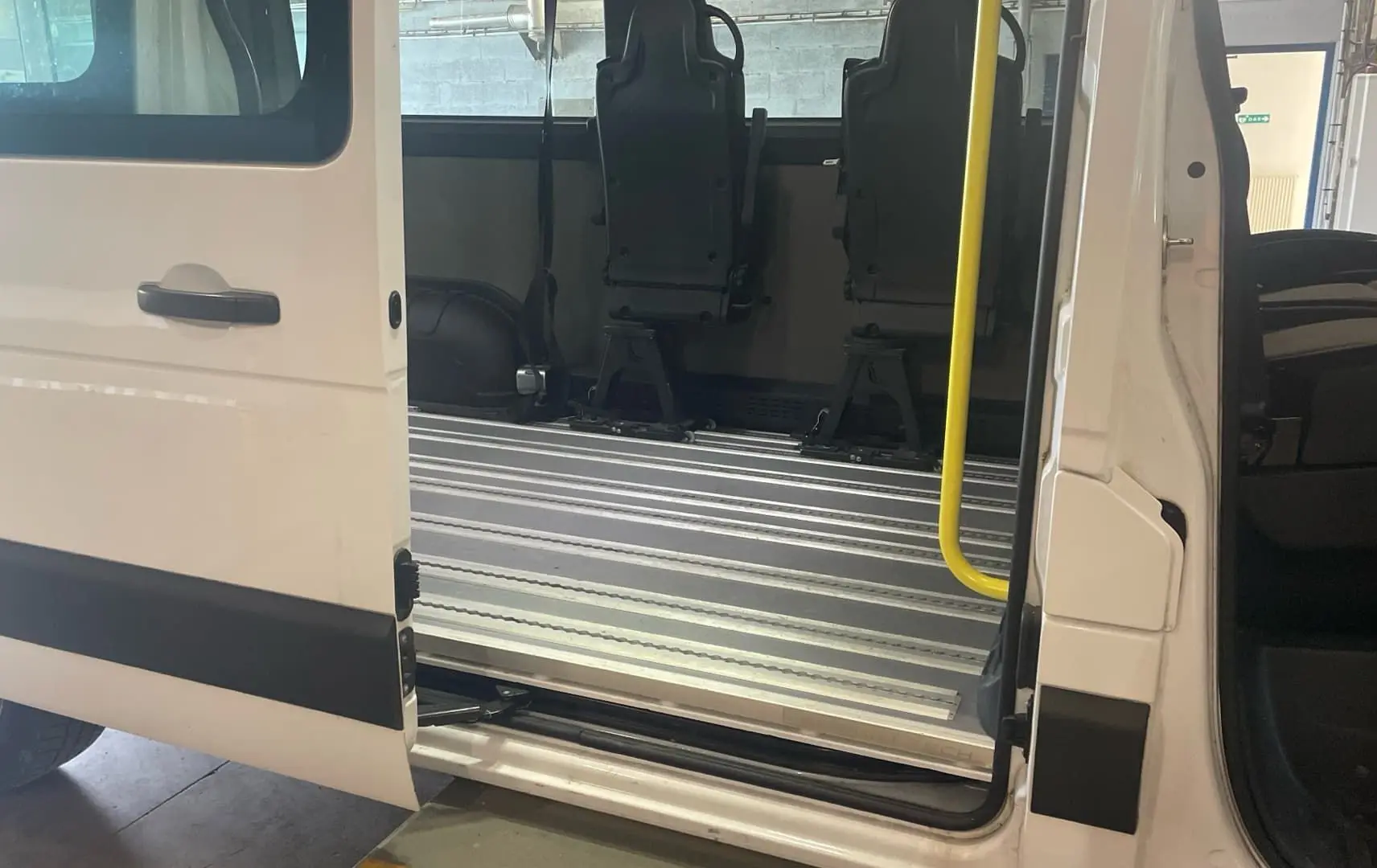 Vue latérale gauche du Renault Master blanc 2019 avec porte coulissante ouverte et sièges adaptés pour fauteuils roulants.