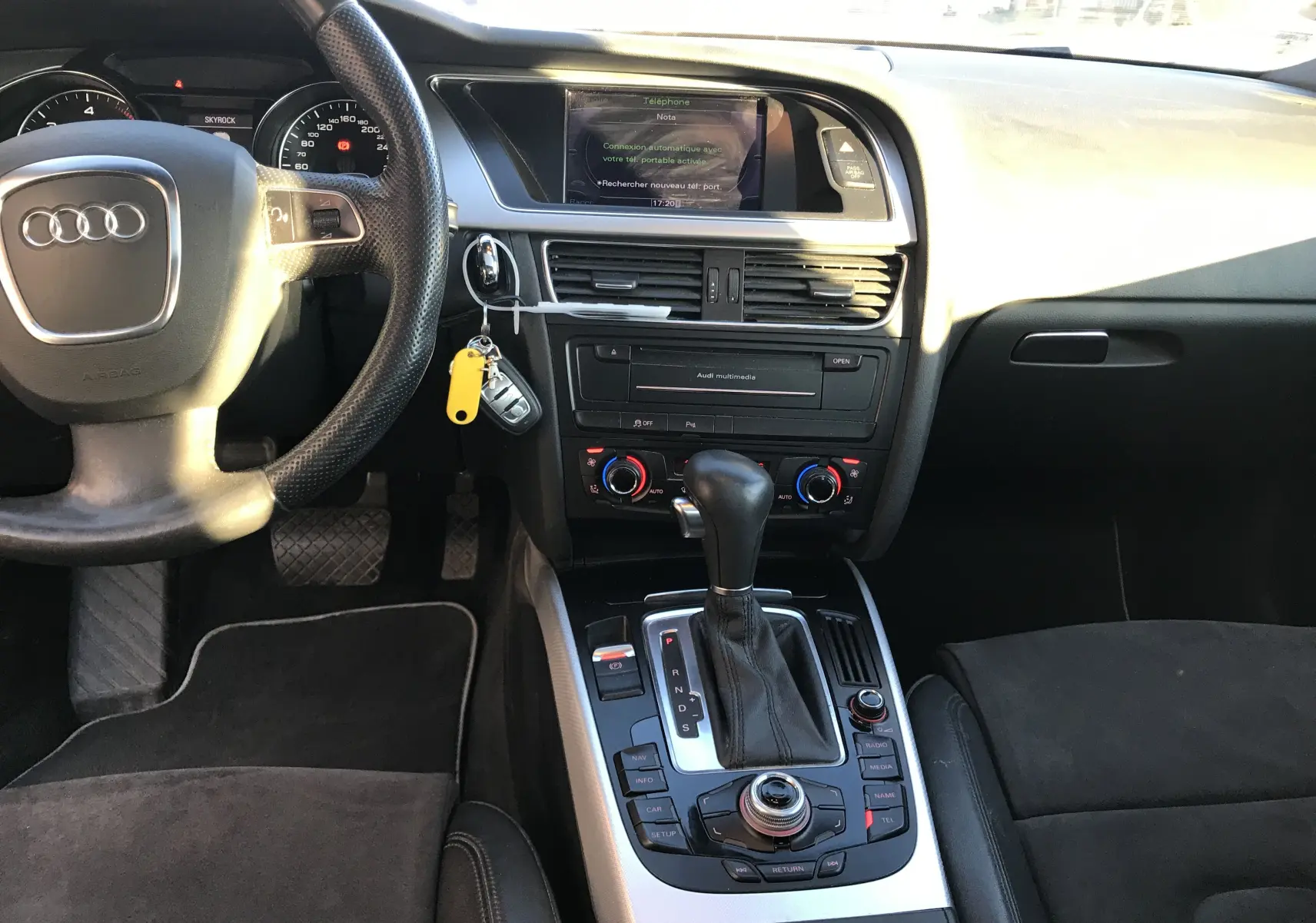 Vue intérieure de l'Audi A5 2012 montrant le tableau de bord, volant, console centrale avec levier de vitesse et écran multimédia.