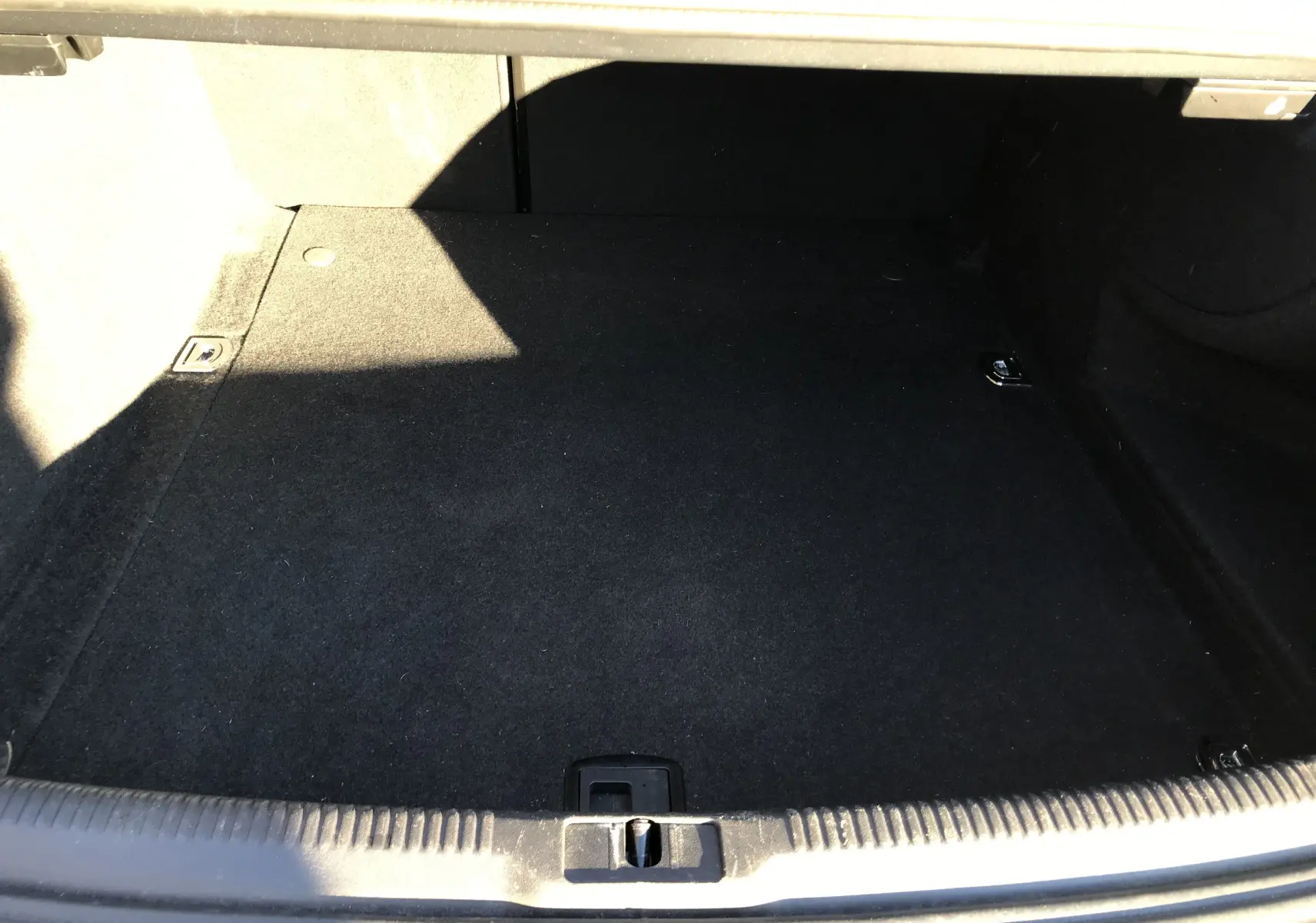 Coffre vide en moquette noire de l'Audi A5 Coupé gris dauphin, vue intérieure depuis l'arrière du véhicule.