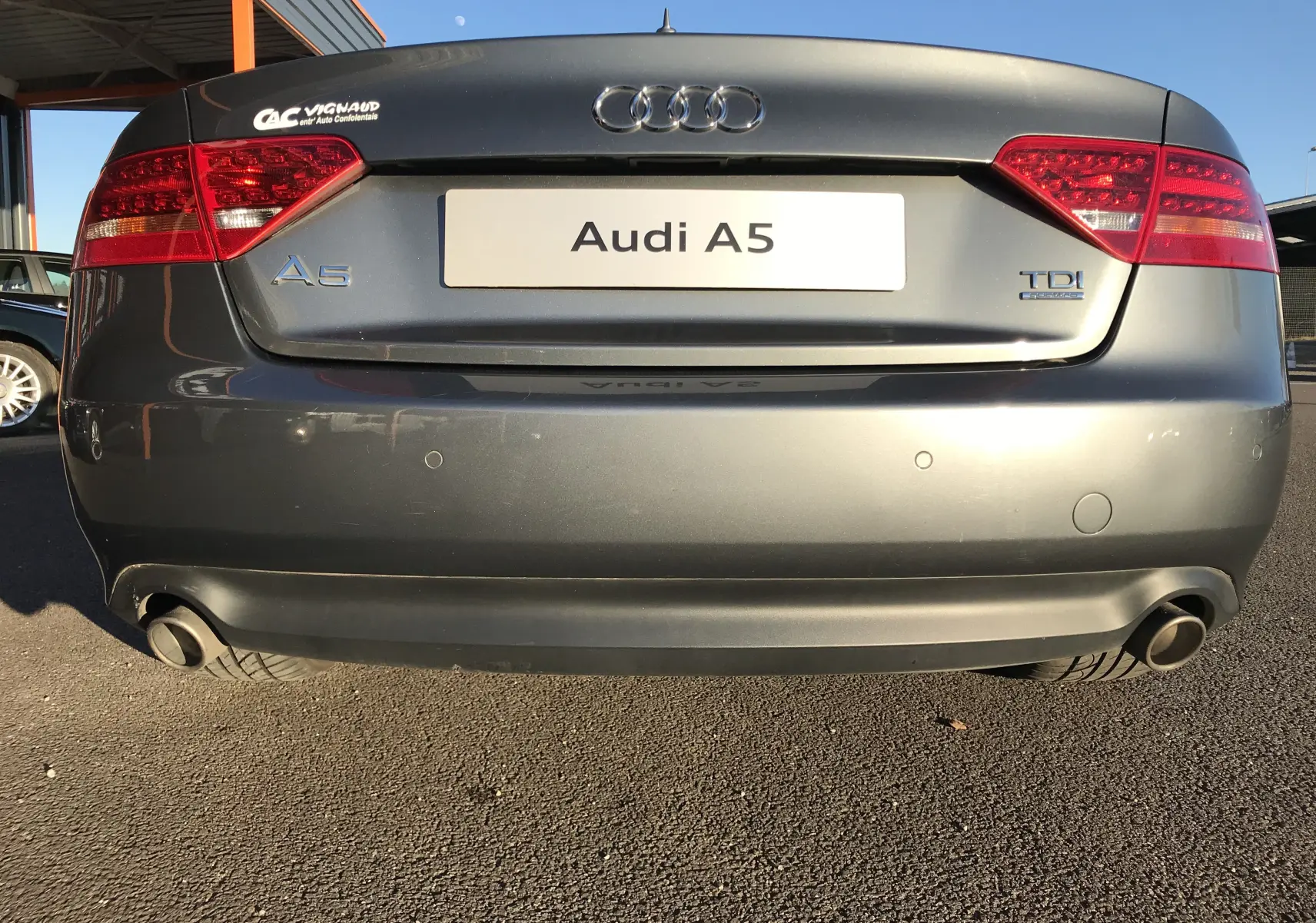Vue arrière d'une Audi A5 Coupé gris dauphin avec logos A5 et TDI visibles sur le coffre.