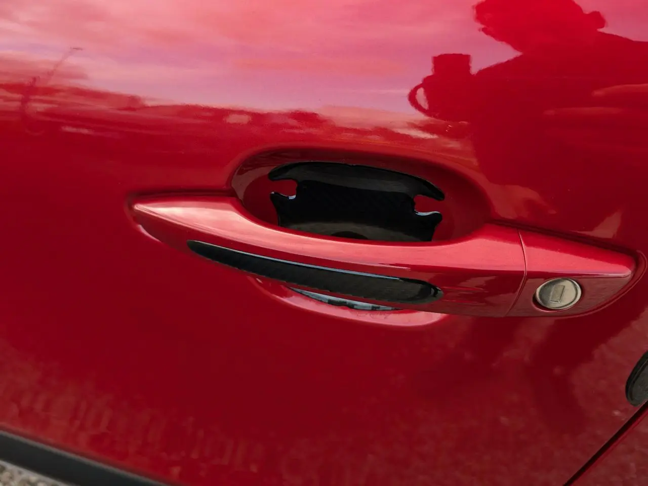 Poignée de porte rouge foncé avec insert noir sur une Citroën C4 2024 vue en gros plan.