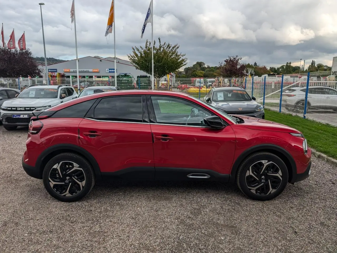 Profil côté gauche d'une Citroën C4 2024 rouge foncé avec jantes alliage noires et vitres surteintées.