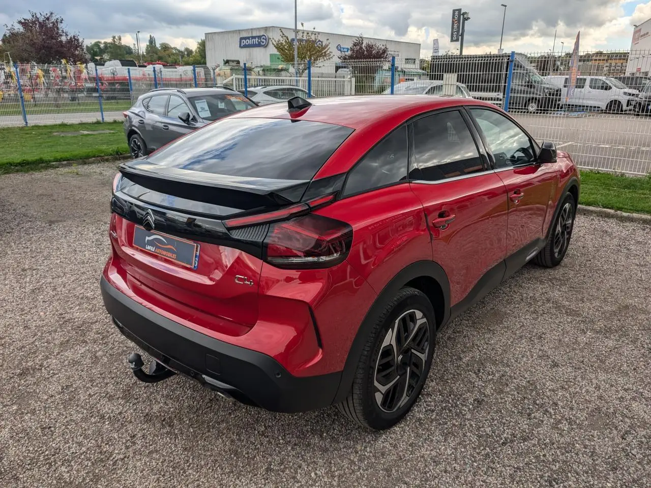Vue 3/4 arrière droite de la Citroën C4 2024 rouge foncé avec attelage col de cygne et jantes alliage 18 pouces.