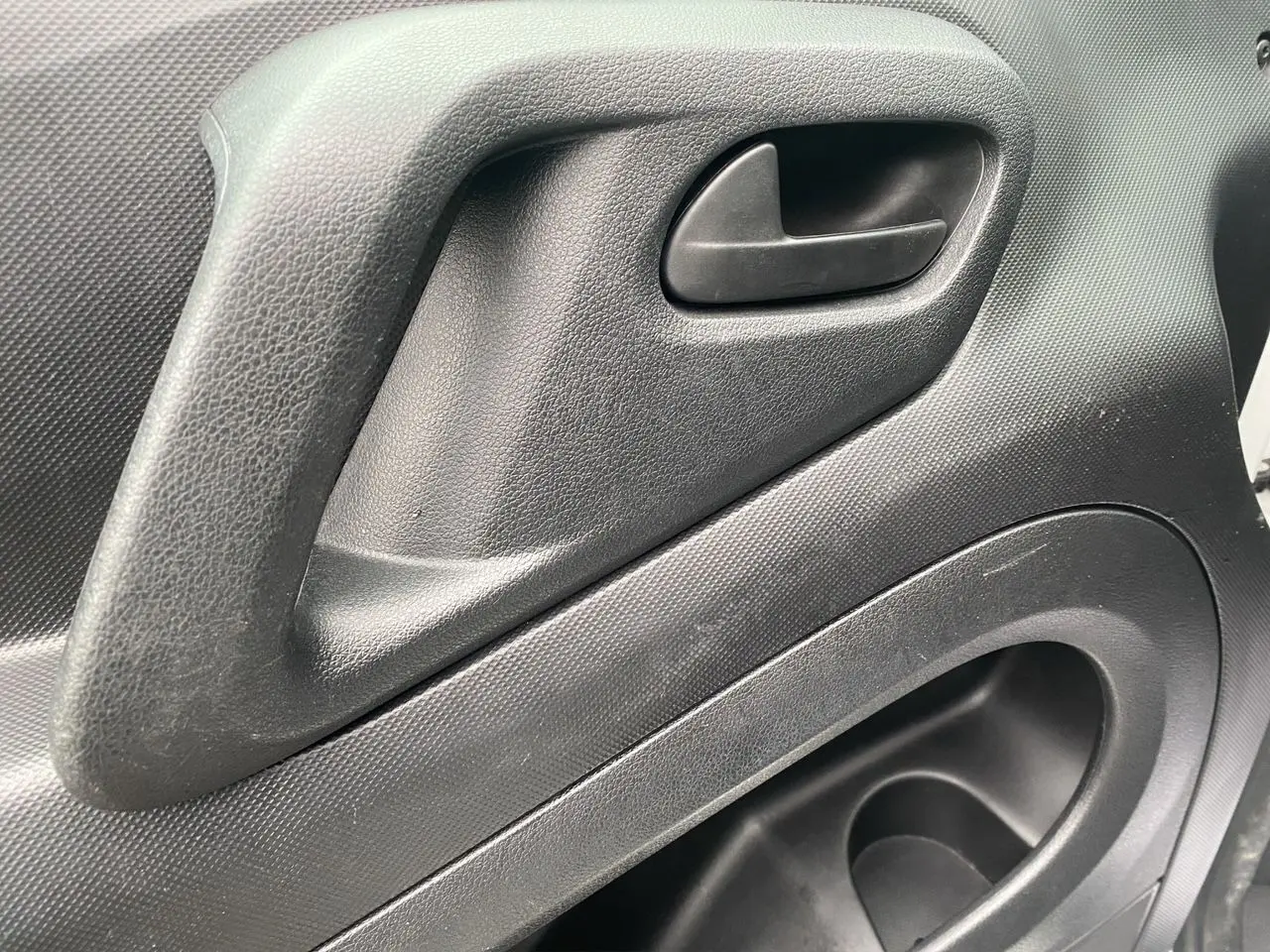 Poignée intérieure de porte côté gauche en plastique noir du Citroën Berlingo blanc, version Van M BlueHDi 2018.