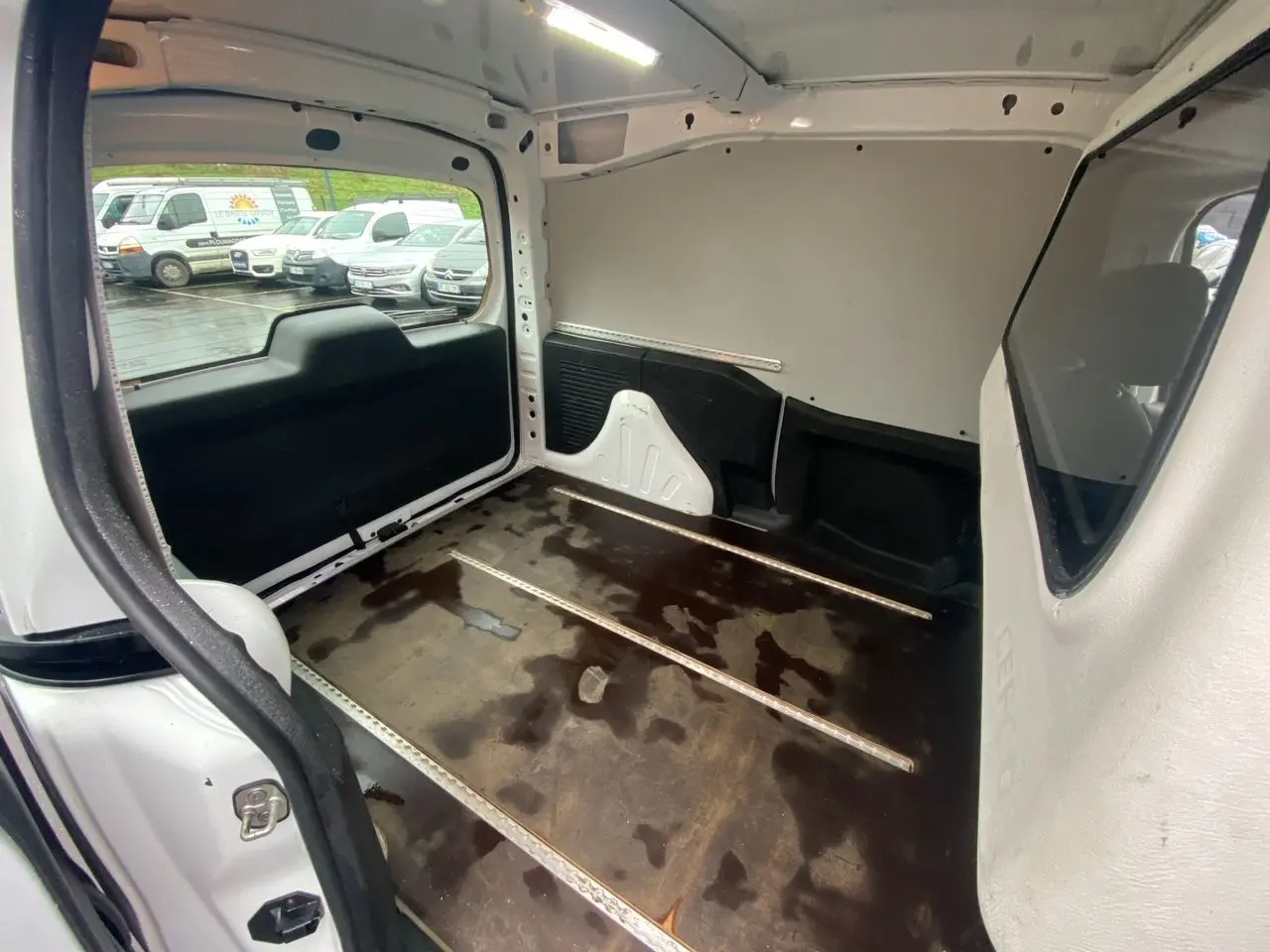 Vue intérieure arrière du Citroën Berlingo blanc 2018, montrant l’espace de chargement vide avec plancher usé.