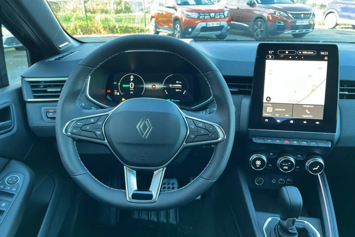 Vue intérieure centrée sur le volant cuir multifonctions et l’écran tactile du tableau de bord de la Renault Clio 2025.
