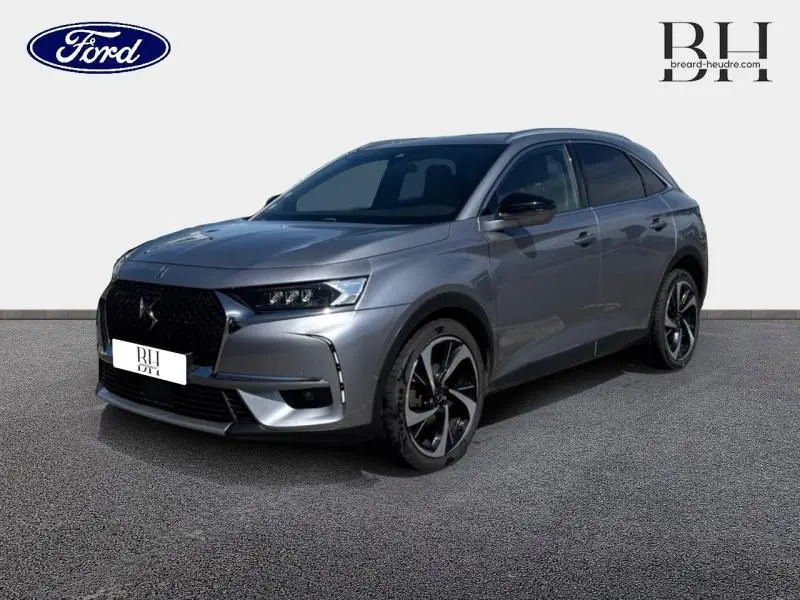DS7 Crossback gris Artense vu en 3/4 avant droit, avec calandre noire et jantes 20 pouces distinctives.