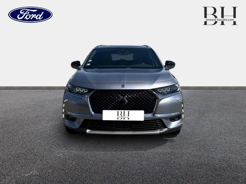 Vue avant d'un DS7 Crossback gris Artense avec calandre noire distinctive et feux LED allumés.