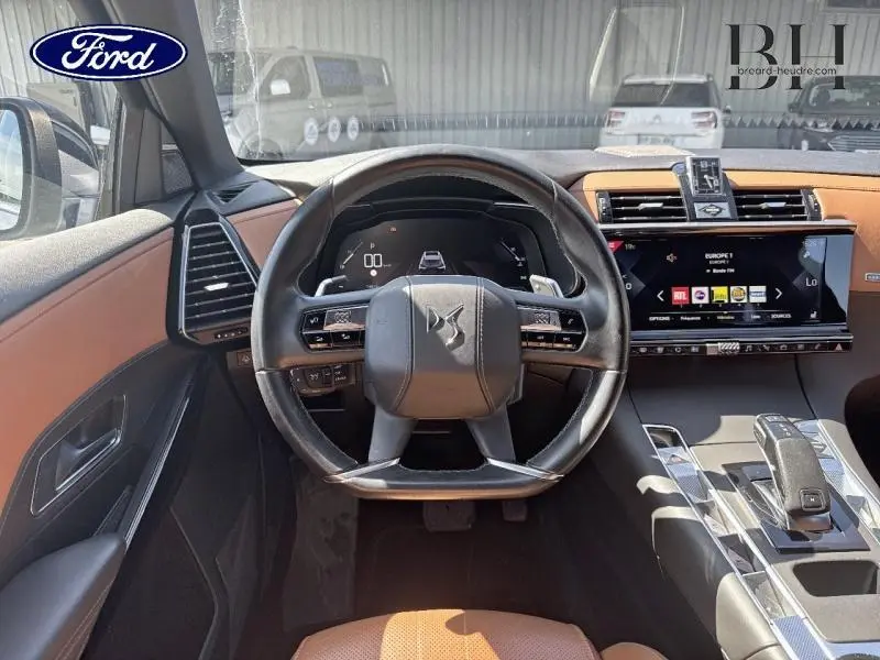 Vue intérieure centrée sur le volant cuir DS d'un DS7 Crossback 2020, avec tableau de bord numérique et sellerie brun alézan.