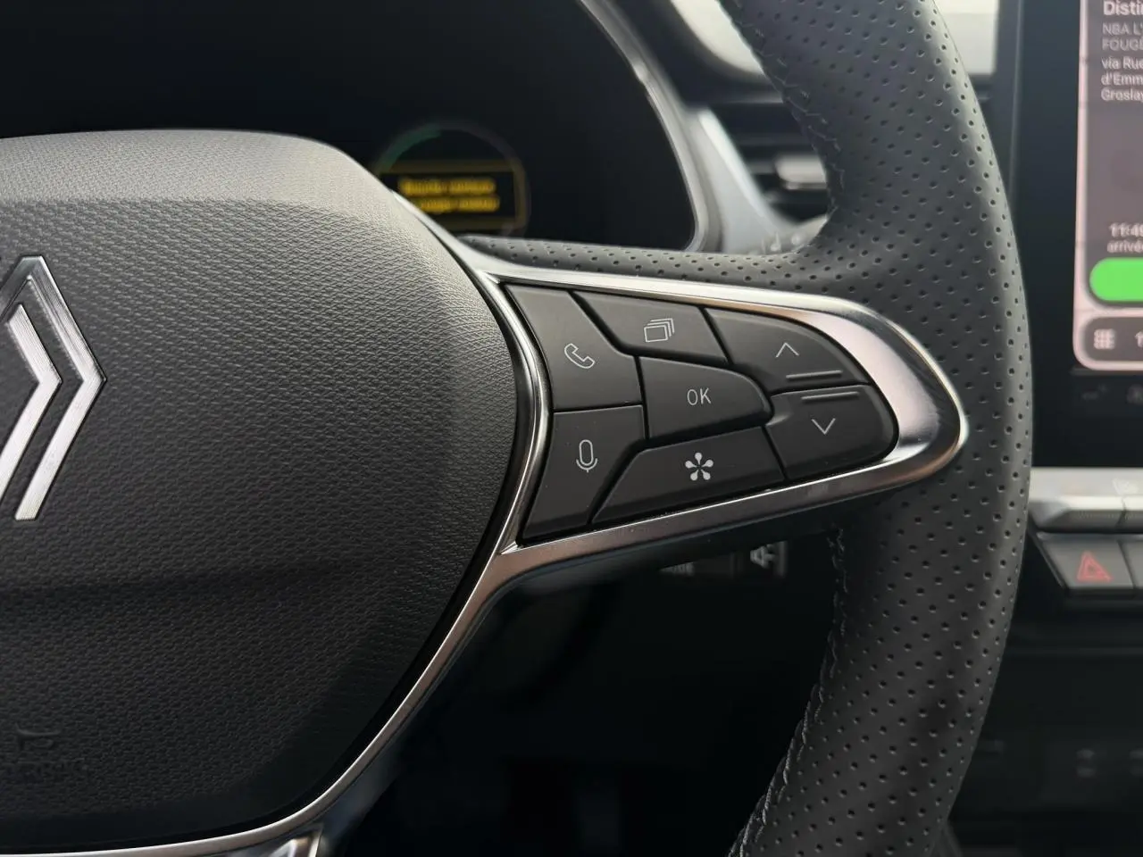 Gros plan sur la partie droite du volant perforé noir du Renault Captur gris Rafale, avec commandes multifonctions visibles.