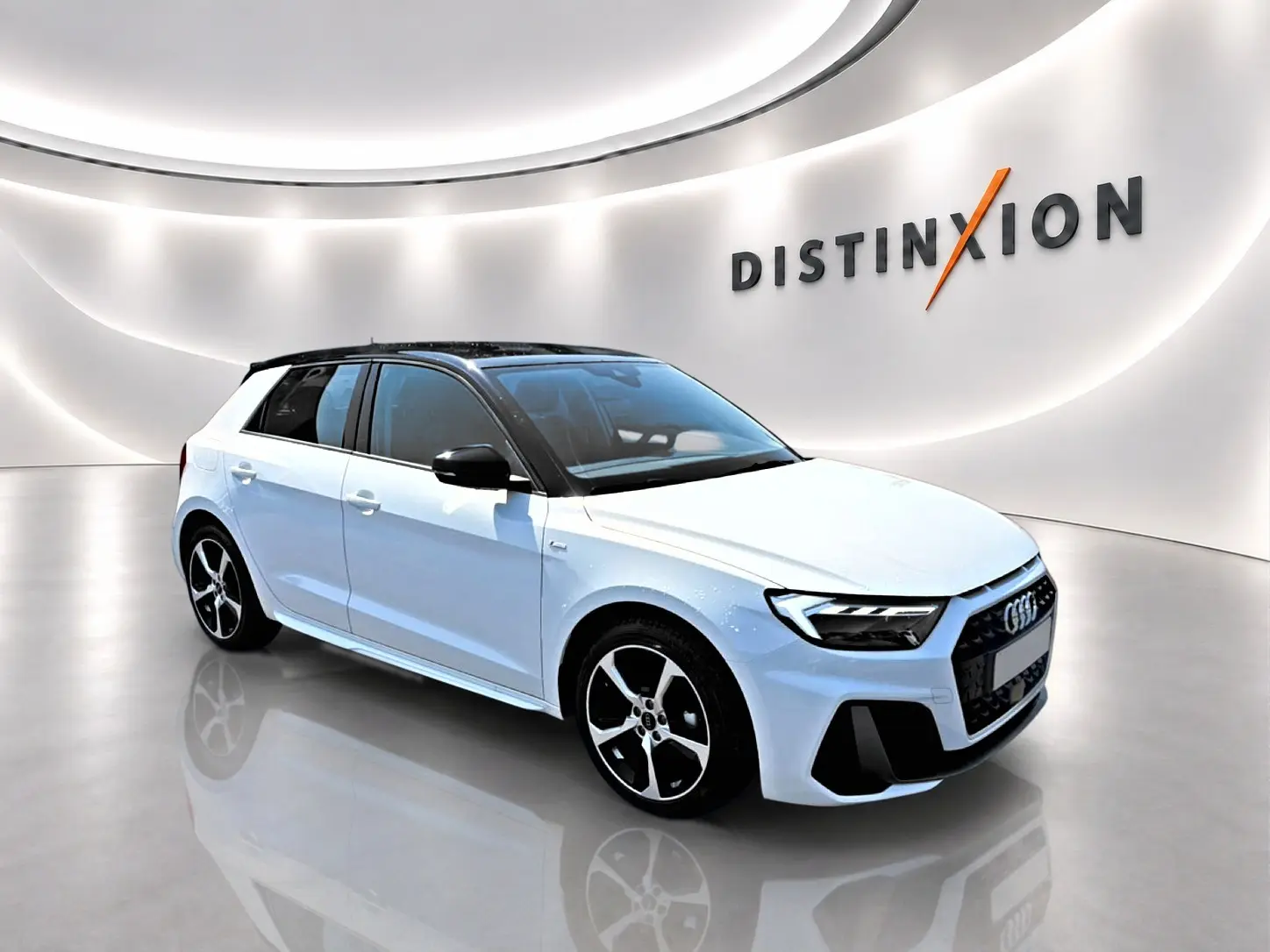 Audi A1 Sportback blanc et noir en 3/4 avant droit, avec jantes alu et toit noir contrasté en showroom lumineux.