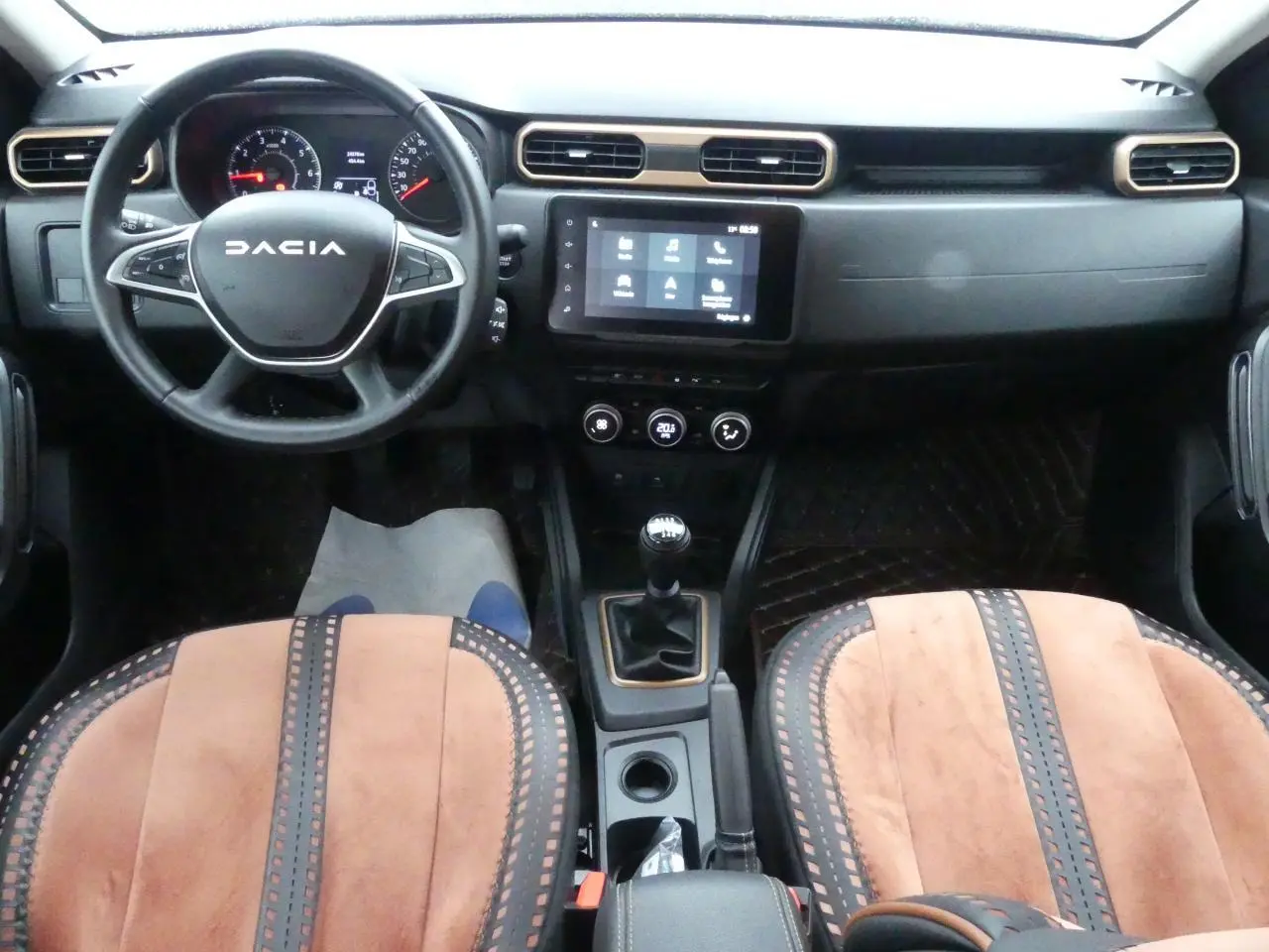 Vue intérieure avant du Dacia Duster 2023 avec volant noir, tableau de bord moderne et sellerie brun cuivré spécifique Extreme.