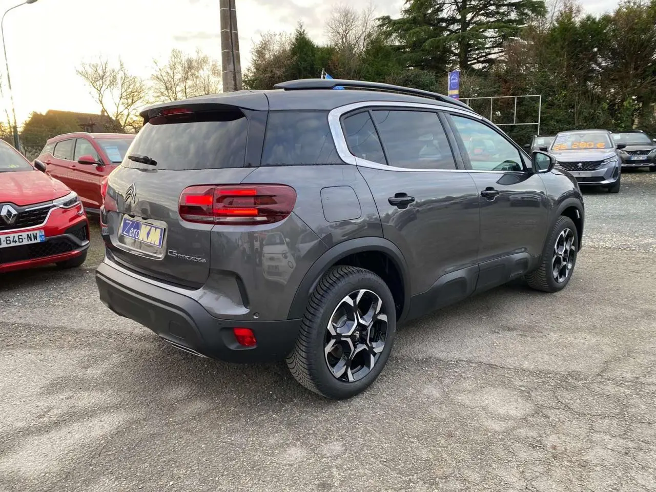 Vue 3/4 arrière droite d'un Citroën C5 Aircross gris platinium avec jantes alliage 18'' bi-ton sur parking.