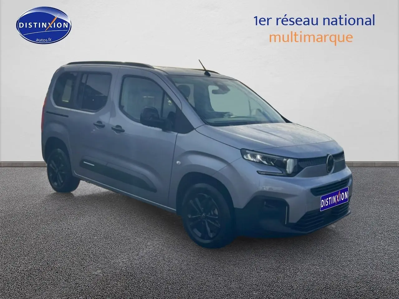Vue 3/4 avant droit d'un Citroën Berlingo 2025 gris Artense avec barres de toit et jantes alu noires.