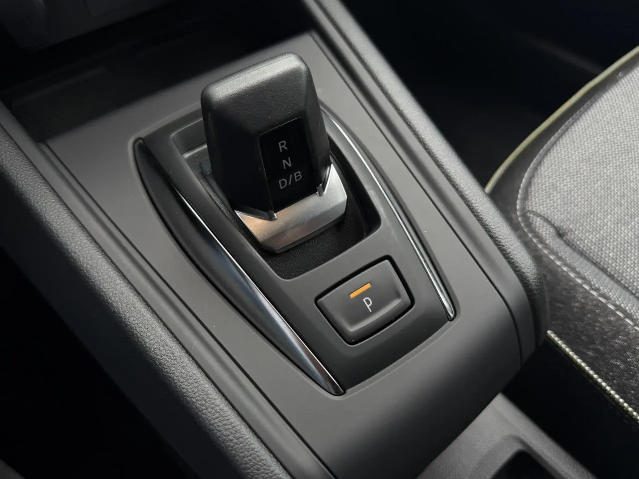 Gros plan sur la commande de boîte automatique noire du Renault Captur gris Rafale, avec bouton de parking éclairé.