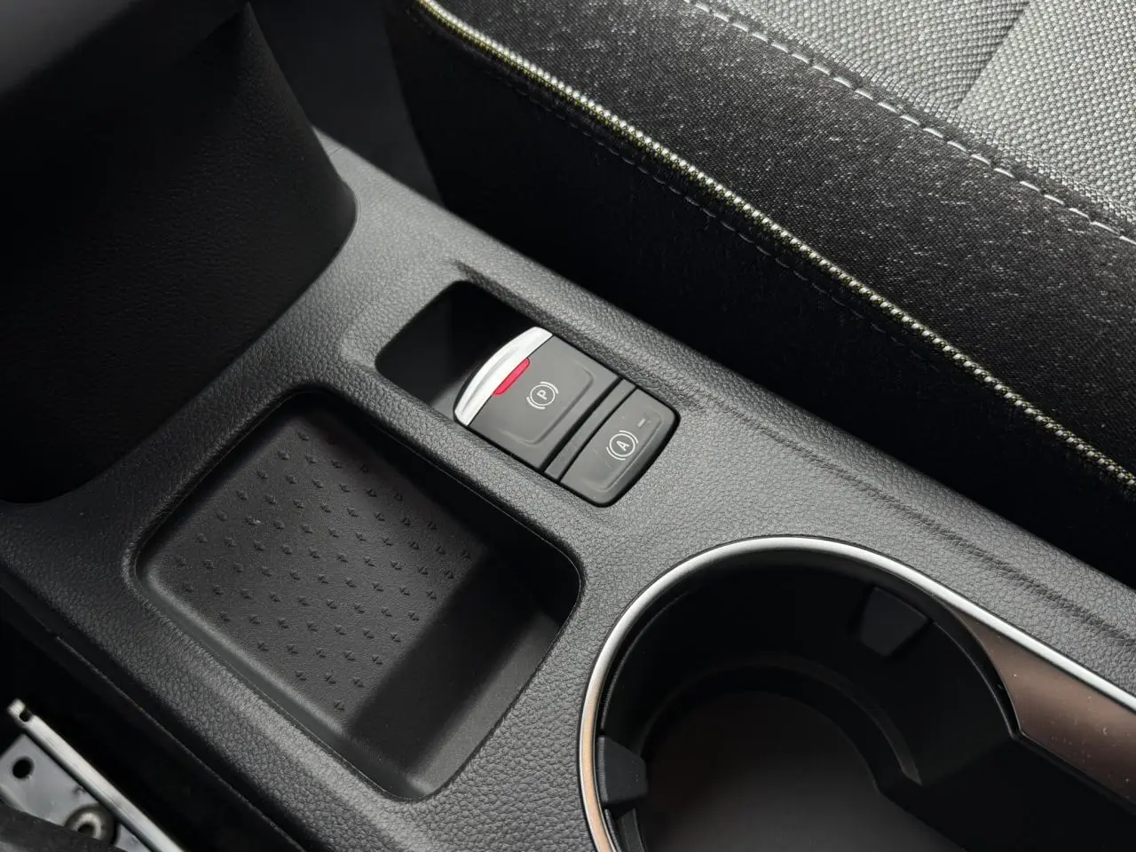 Gros plan sur la console centrale noire du Renault Captur 2026, avec bouton frein électrique et rangement à côté du siège.