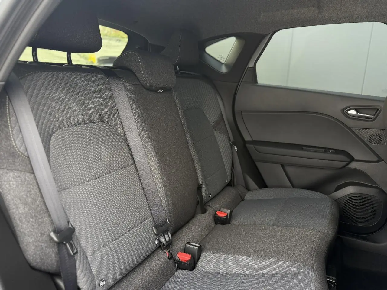 Vue intérieure côté droit des sièges arrière gris foncé du Renault Captur 2026 avec ceintures et appuie-têtes intégrés.
