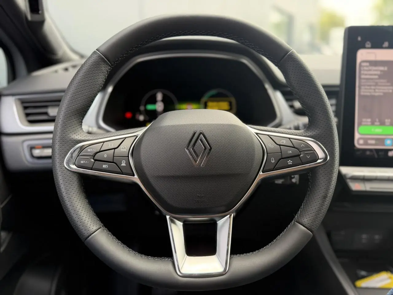 Gros plan sur le volant en cuir perforé du Renault Captur 2026, avec commandes intégrées et tableau de bord numérique flou.