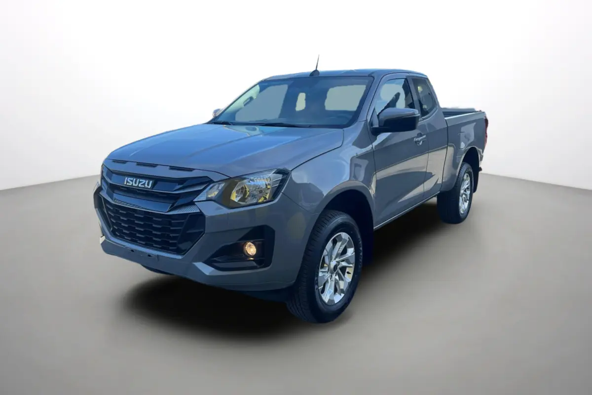 Vue 3/4 avant d’un pick-up Isuzu D-MAX gris Kinabalu avec jantes alu et feux allumés sur fond neutre.