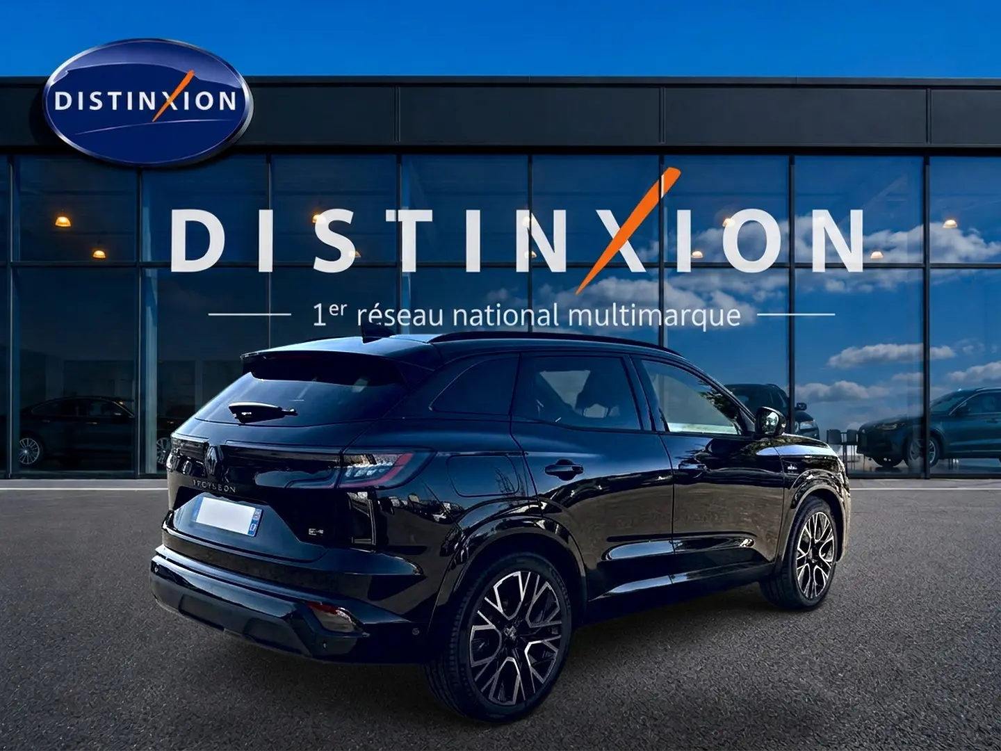 Renault Austral noir en 3/4 arrière droit, avec jantes alu et becquet arrière, devant un bâtiment Distinxion.