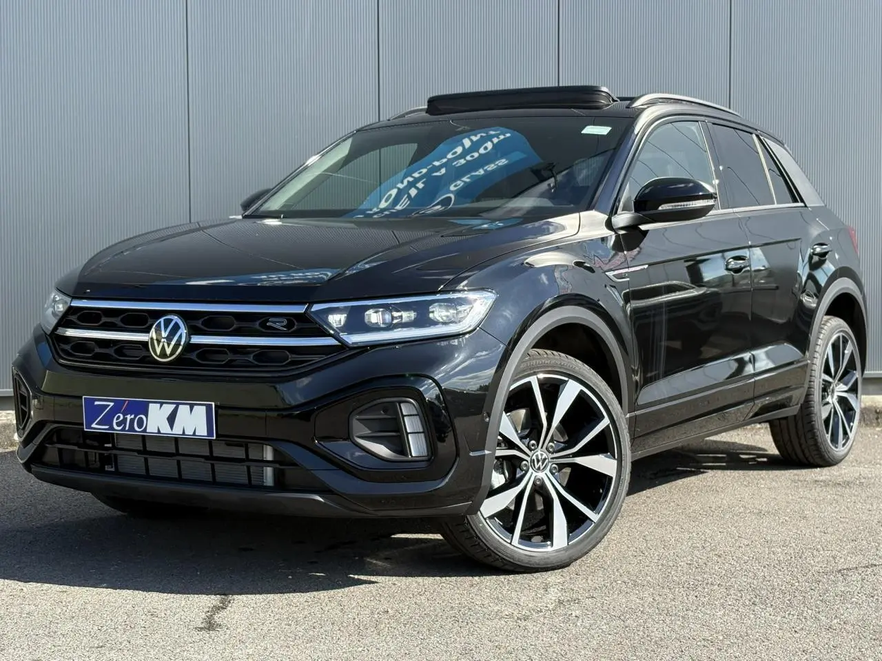 Volkswagen T-Roc noir Grenadilla en 3/4 avant droit avec jantes alliage 19 pouces et toit ouvrant visible.