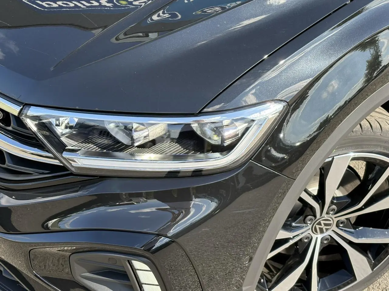 Gros plan sur l'avant droit noir Grenadilla du Volkswagen T-Roc 2025 avec projecteur LED et jante alliage R-Line.