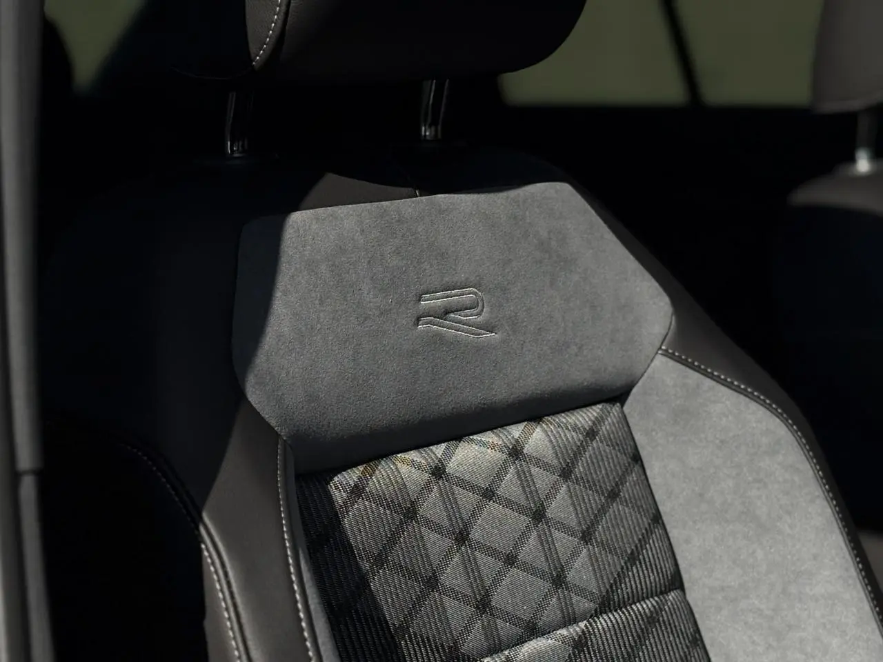 Gros plan sur le siège avant gris et noir du Volkswagen T-Roc R-Line 2025 avec logo R brodé sur l'appuie-tête.