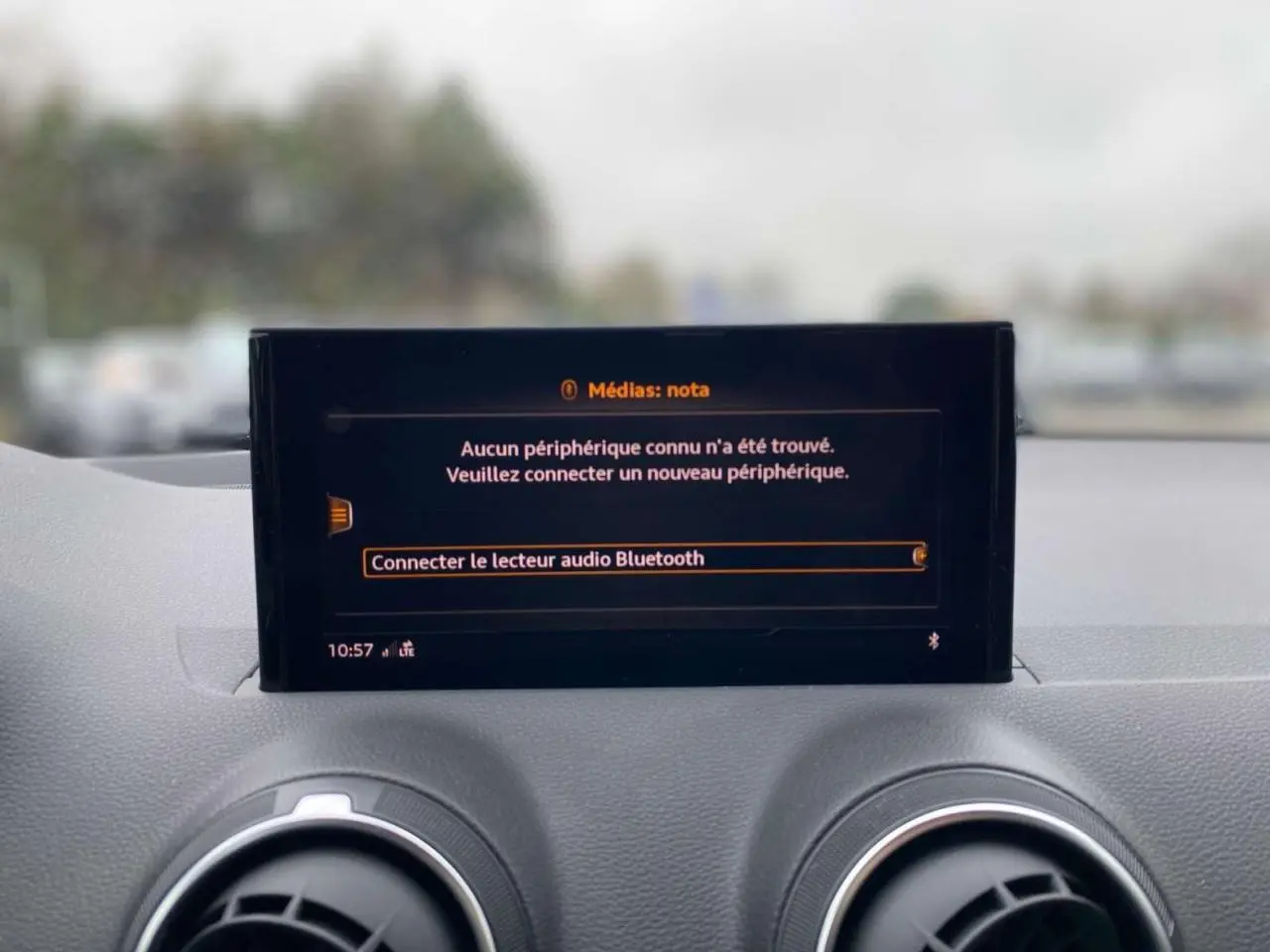 Écran central du tableau de bord de l'Audi Q2 2023 affichant la connexion Bluetooth, entouré de deux aérateurs ronds.