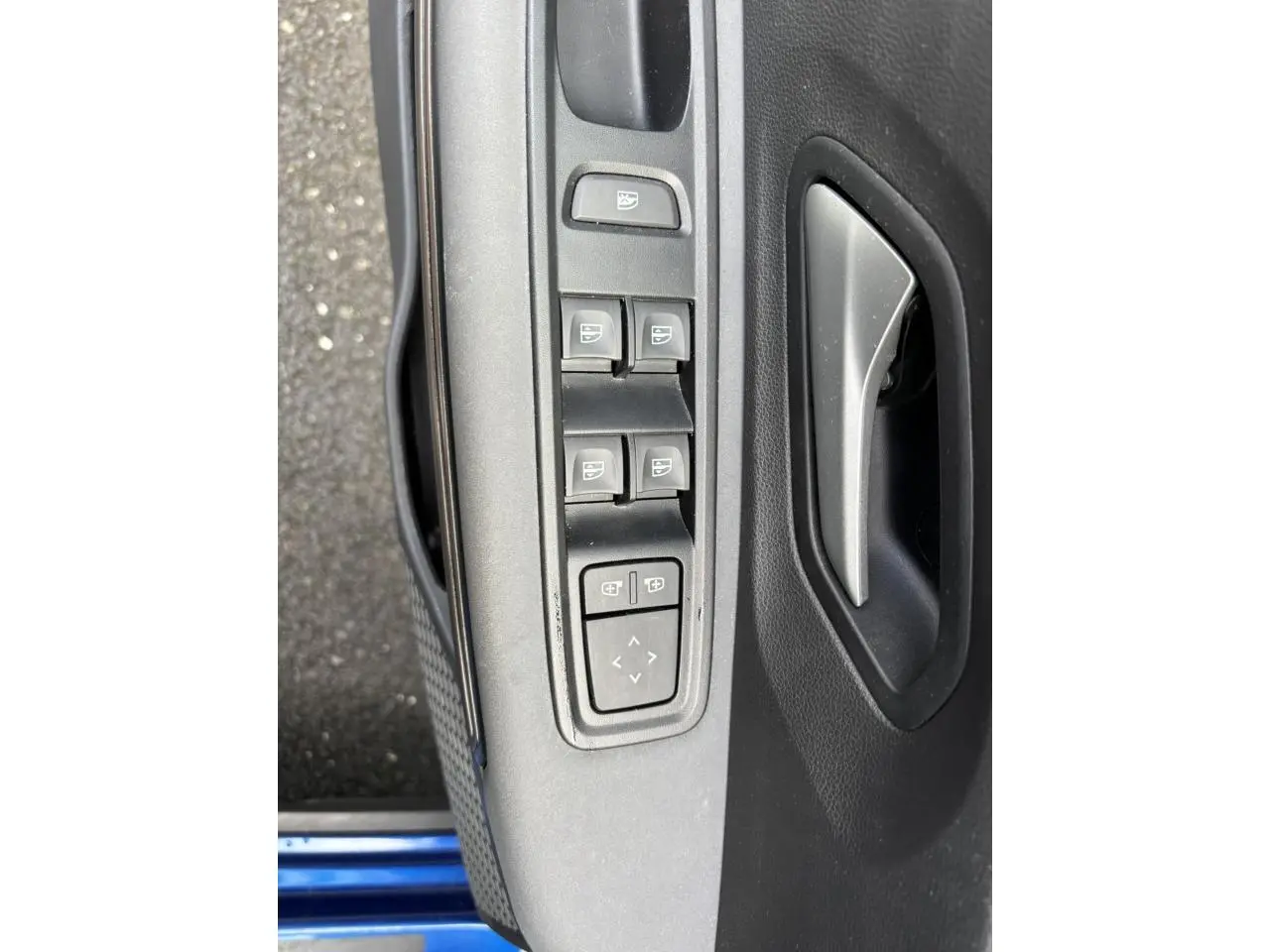 Gros plan sur la commande des vitres électriques et rétroviseurs côté conducteur d'une Dacia Sandero Stepway Bleu Iron.