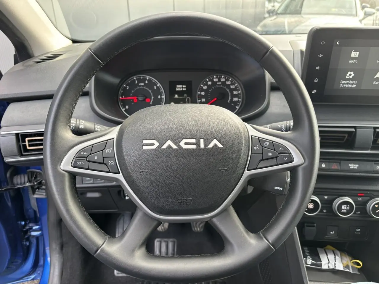Vue intérieure centrée sur le volant noir Dacia avec tableau de bord et écran tactile du Dacia Sandero Stepway Bleu Iron 2025.