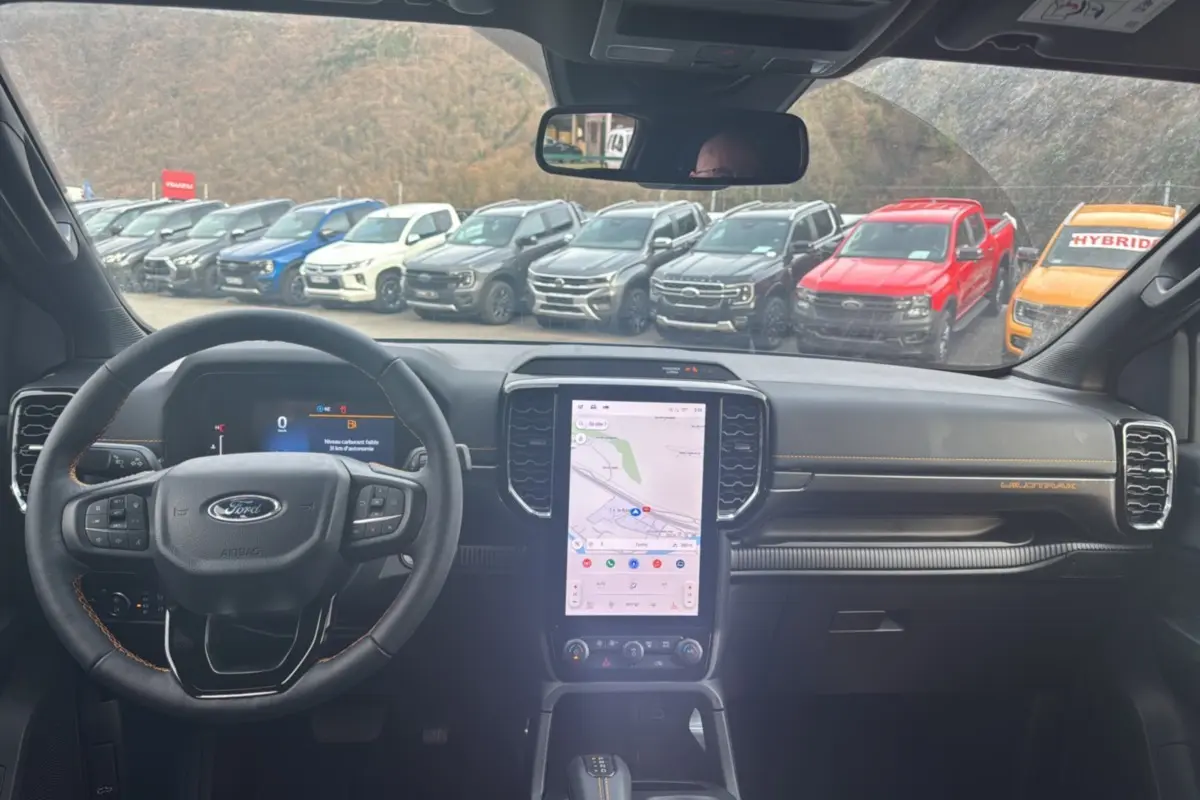 Vue intérieure du Ford Ranger Wildtrak 2025, montrant le tableau de bord noir avec écran tactile vertical et volant multifonctions.