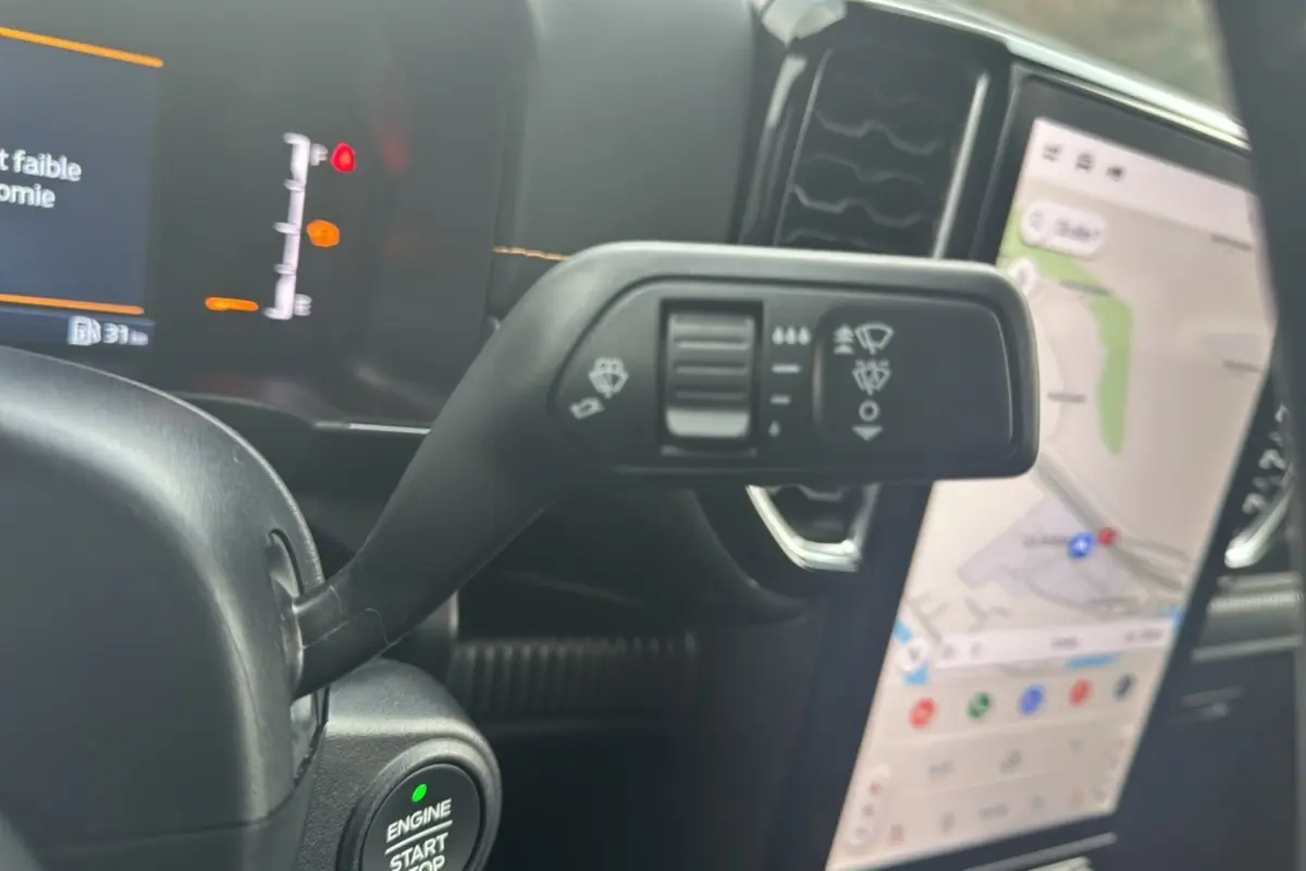 Gros plan sur le commodo de commande d’essuie-glace et le bouton start/stop du Ford Ranger Wildtrak 2025, intérieur noir.
