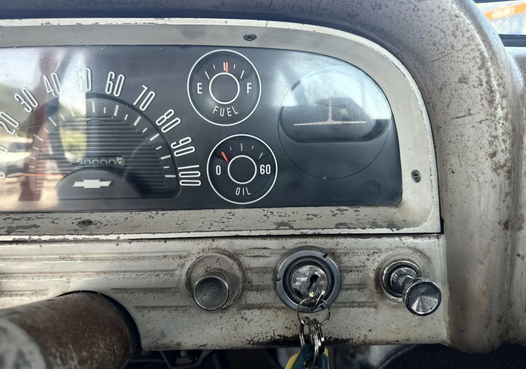Tableau de bord ancien de Chevrolet C10 Apache 1963, vue frontale sur compteurs et clé de contact insérée.