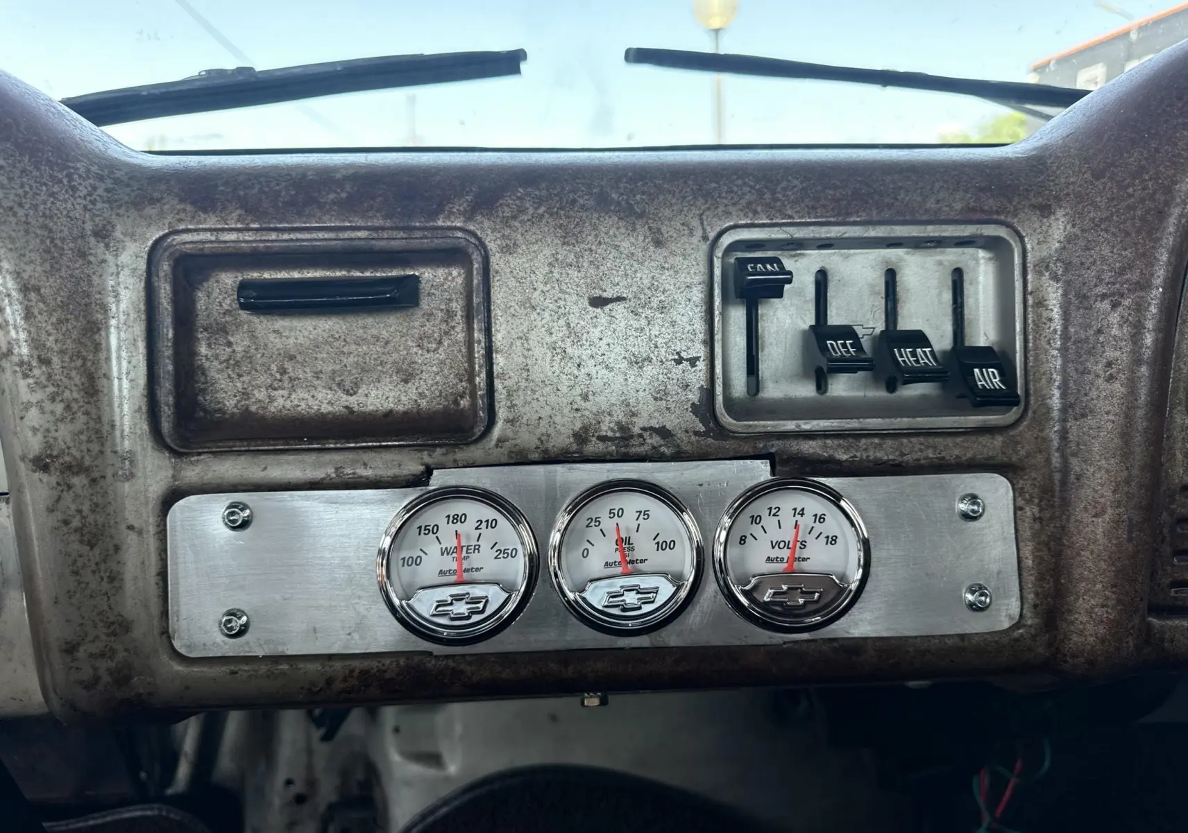 Tableau de bord ancien vu de face du Chevrolet C10 Apache 1963, avec jauges rondes et commandes d’air vintage.