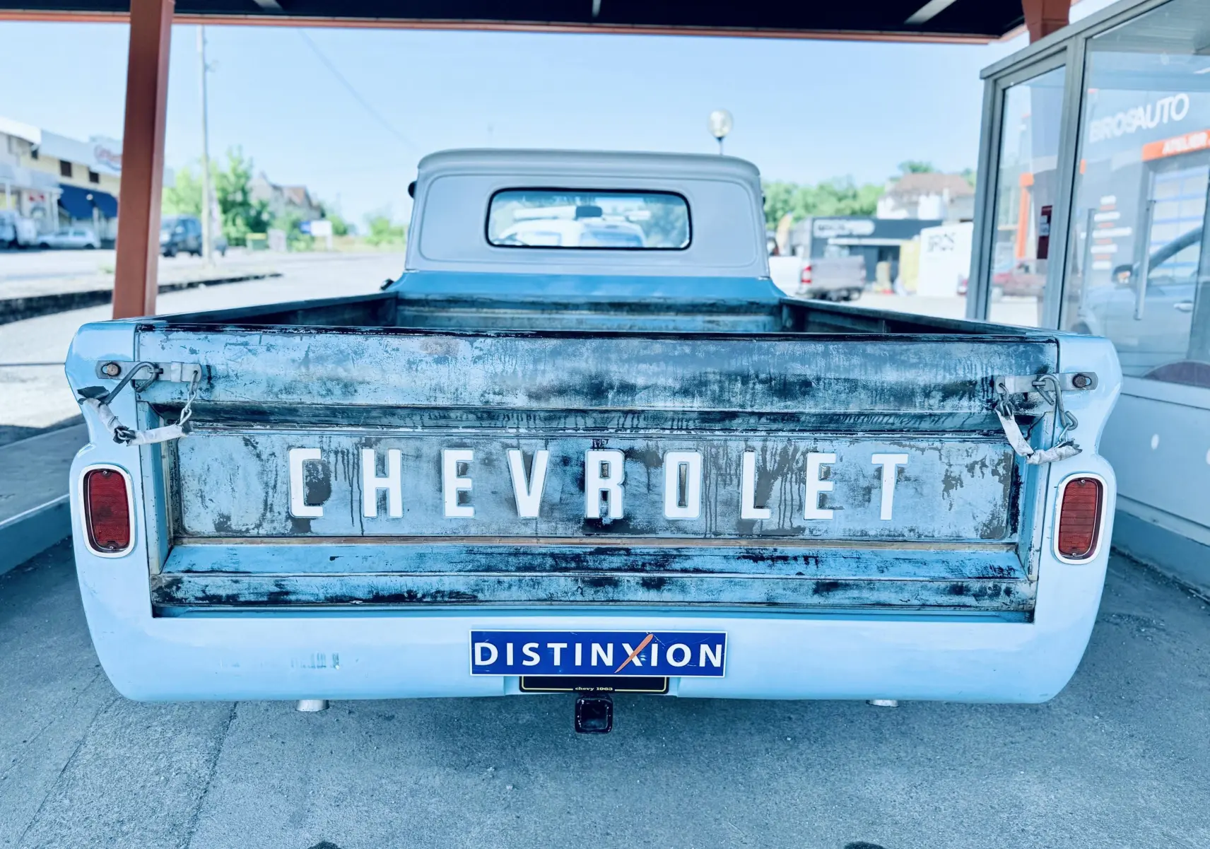 Vue arrière d’un Chevrolet C10 Apache 1963 bleu avec la benne usée et le logo Chevrolet en relief.