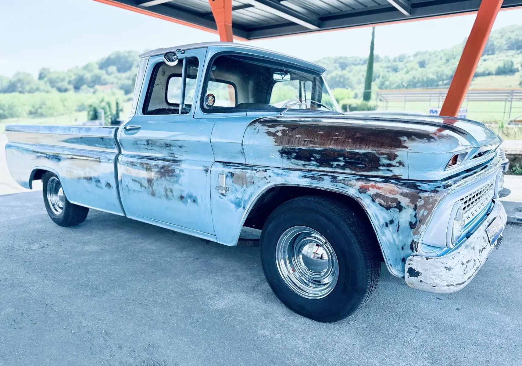Chevrolet C10 Apache 1963 bleu patiné, vue 3/4 avant droit sous abri avec carrosserie vieillie et jantes chromées.