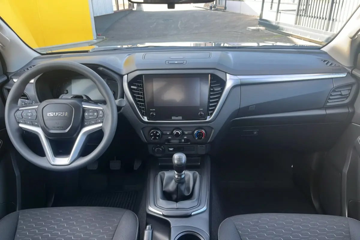 Vue intérieure avant de l'Isuzu D-MAX 2026 avec tableau de bord noir et volant multifonctions.