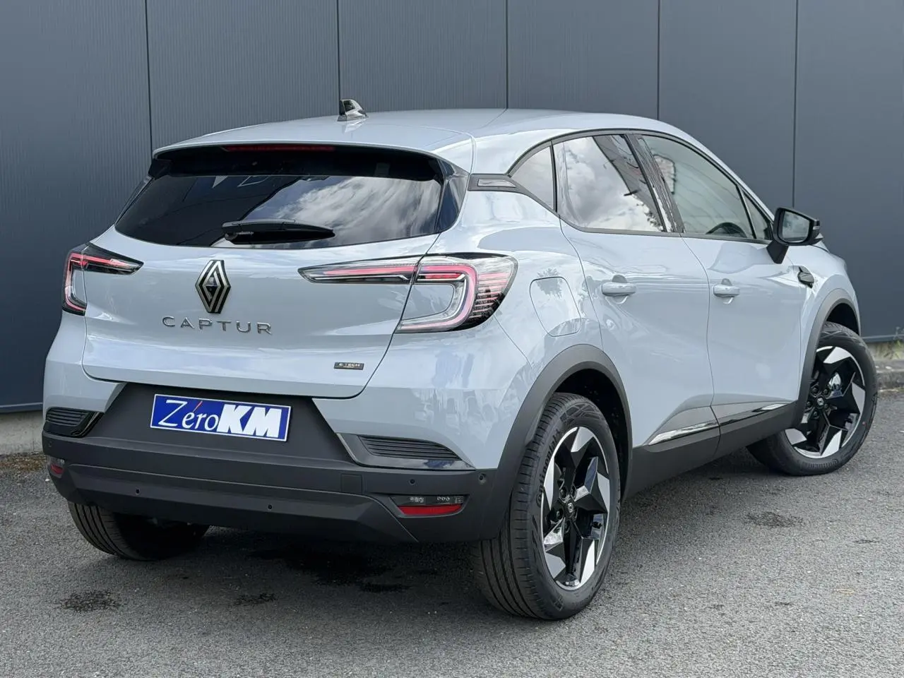 Vue 3/4 arrière droite du Renault Captur gris Rafale avec jantes noires et vitres surteintées.